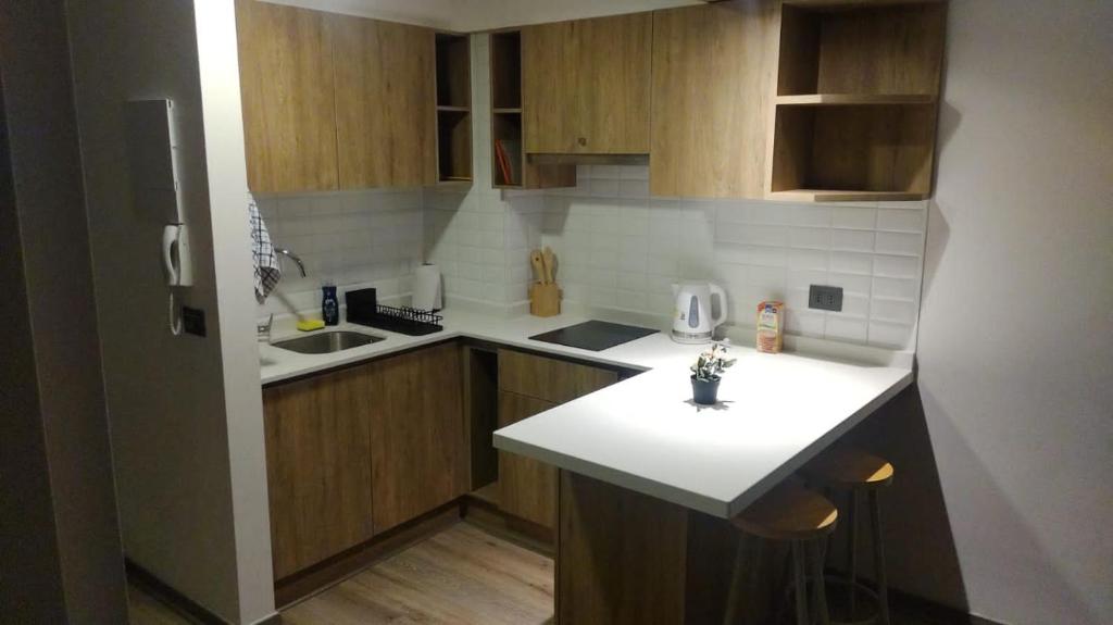a kitchen with a white counter top and wooden cabinets at Apartamento La Florida Mirador Oriente in Santiago