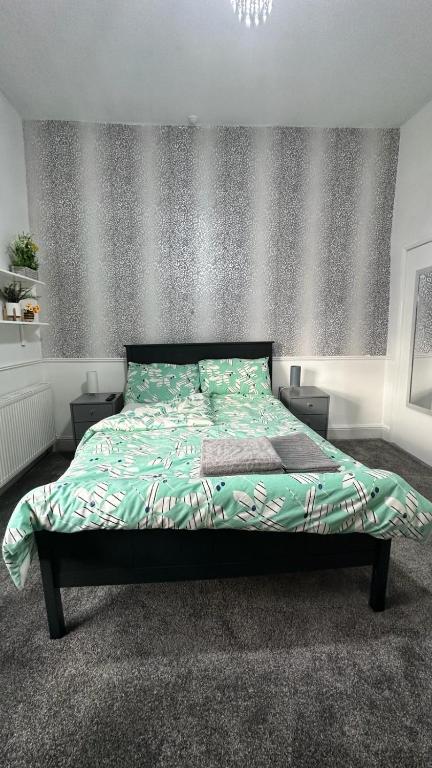 a bed with a green comforter in a bedroom at Ur Place 204 in Manchester