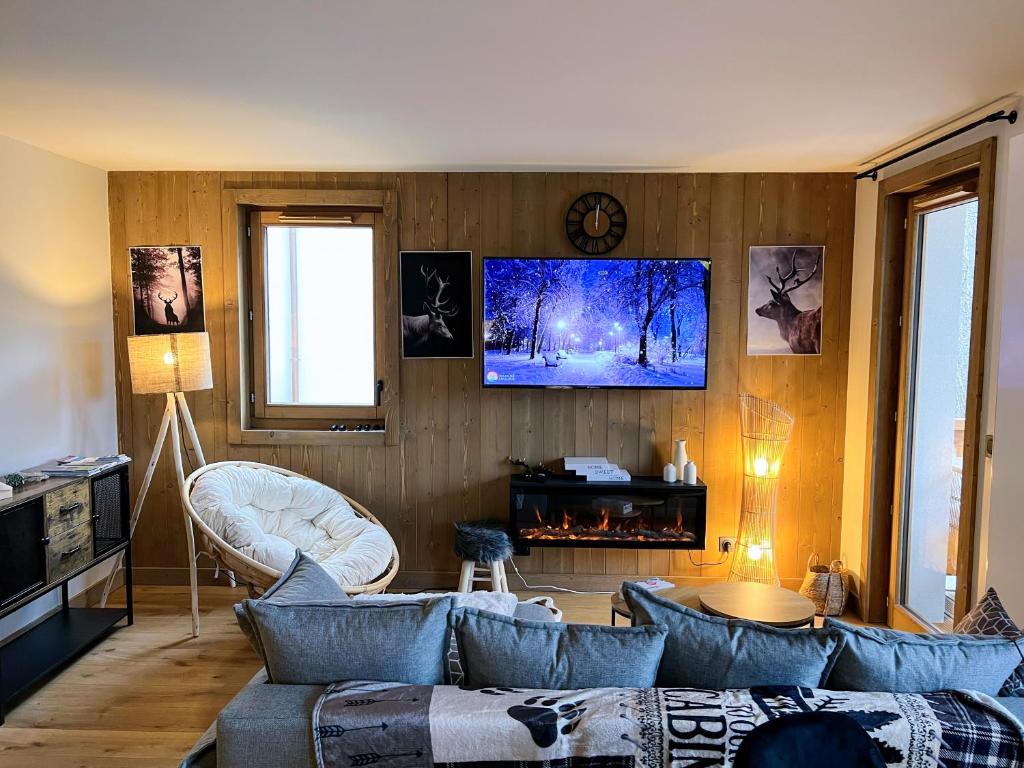 a living room with a couch and a tv on a wall at Cabana & L Altima Megeve Service in Megève