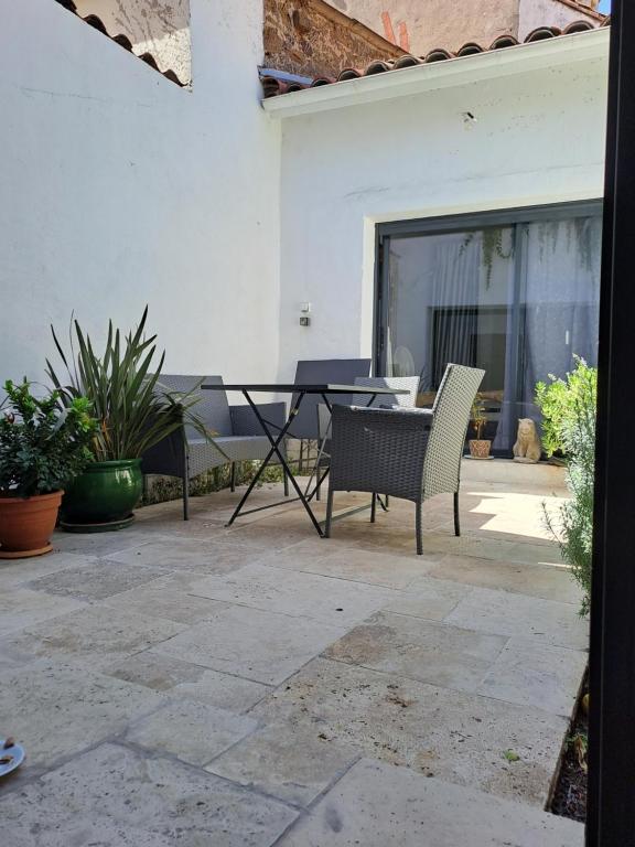 un patio avec une table et des chaises sur un patio dans l'établissement Belle maison de village entièrement climatisée, à Vias