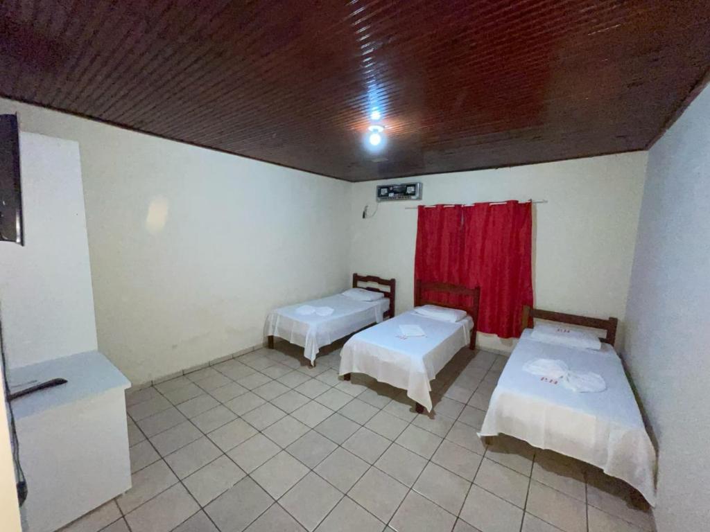 Habitación con 2 camas y cortina roja. en Plaza Hotel, en Jataí