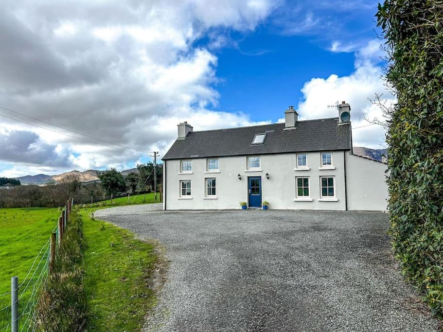 ein weißes Haus auf einer Schotterstraße in der Unterkunft Sneem Farmhouse in Sneem