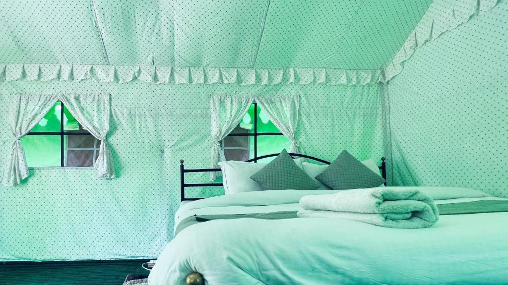 a green bedroom with two beds and two windows at The Himalayan Cottage Camping With Bonfire, Manali - Riverside in Manāli
