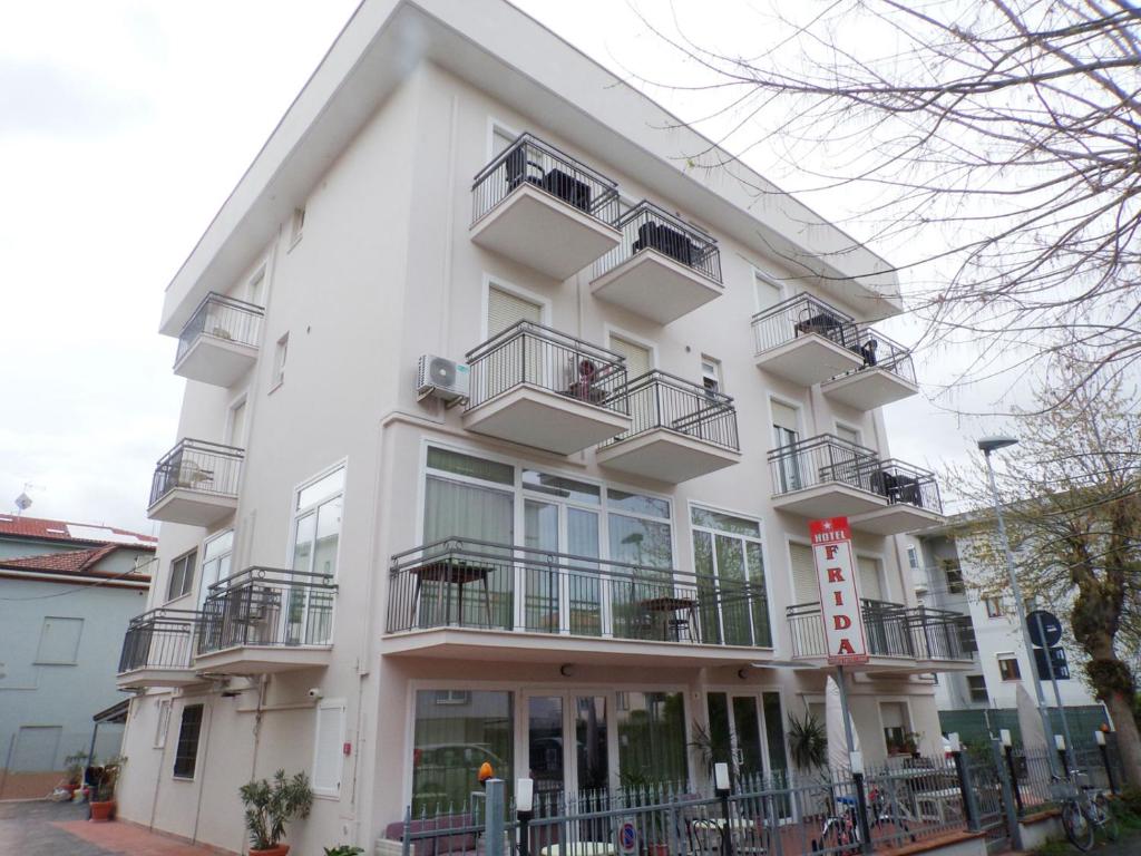 een wit gebouw met balkons in een straat bij Hotel Frida in Rimini