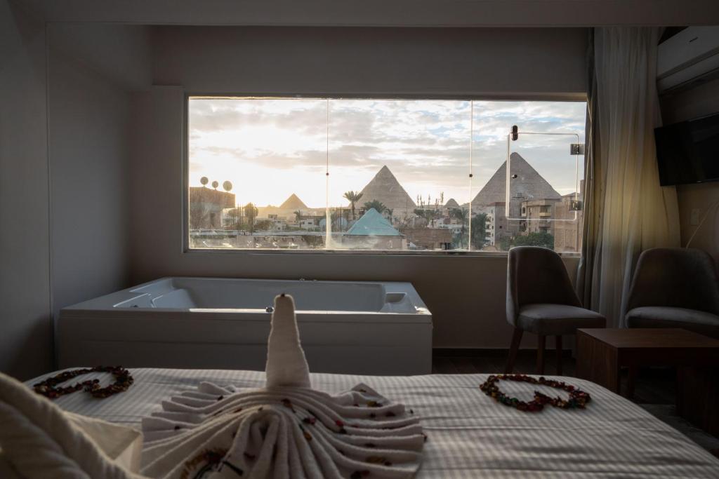 a bedroom with a tub and a window with a view of pyramids at Tuya Pyramids Inn hotel in Cairo