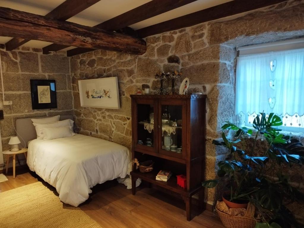 1 dormitorio con cama y pared de piedra en Casa Elvira, en San Amaro
