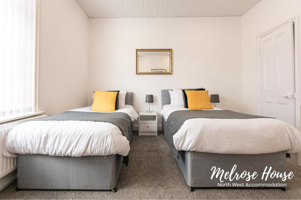1 Schlafzimmer mit 2 Betten und einem Wandspiegel in der Unterkunft Melrose Contractor Accommodation in Manchester
