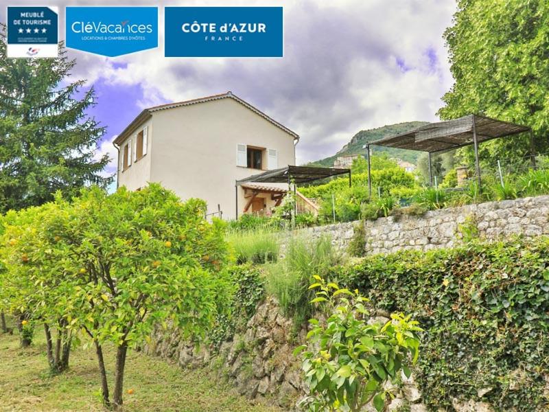 une maison blanche avec un mur en pierre et des arbres dans l'établissement Locations-06 La maison de Noélie 1er étage, gite pour 6 au calme sur la Côte d'Azur, à Le Bar-sur-Loup