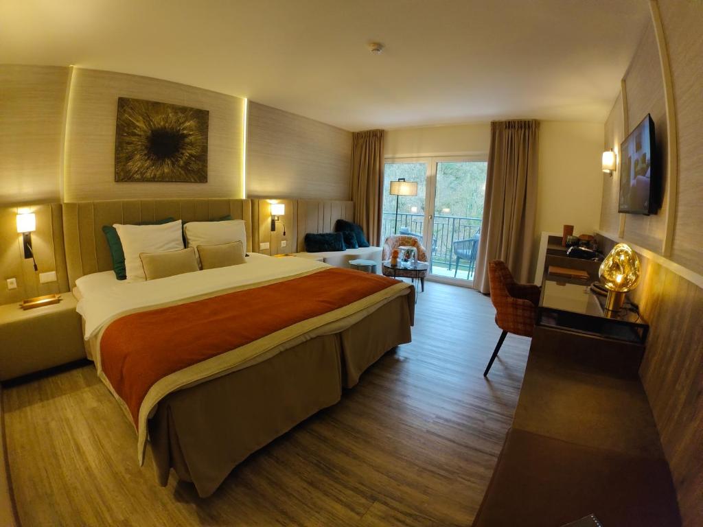a hotel room with a large bed and a balcony at Cocoon Hotel Belair in Bourscheid