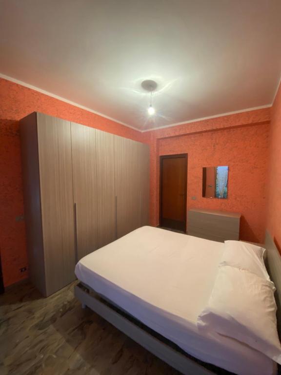 una camera con un letto bianco e una parete arancione di La villetta a Caulonia Marina