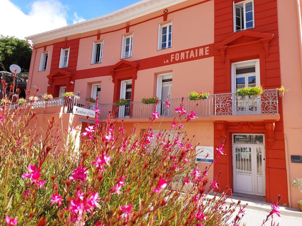 un edificio con flores rosas delante de él en La Fontaine - Chambres d'Hôtes en Olette