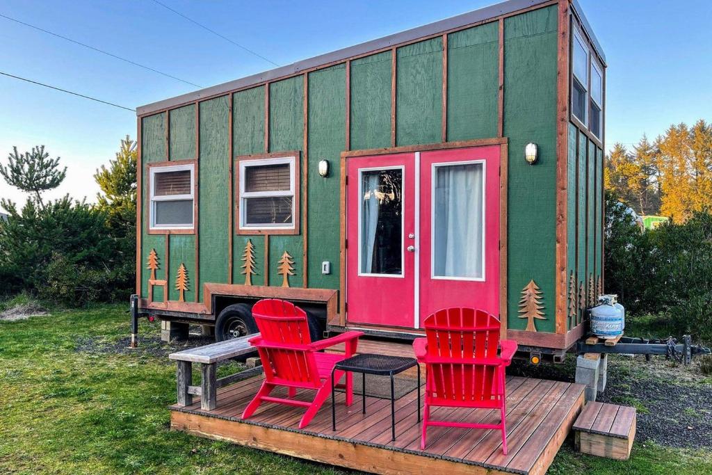 een groen en roze tiny house met twee rode stoelen bij Evergreen in Waldport