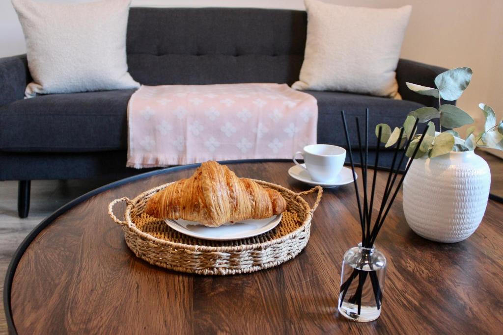 a coffee table with a basket of bread and a cup of coffee at Chic & Cushy 3 Bed House, short and long term in Birmingham