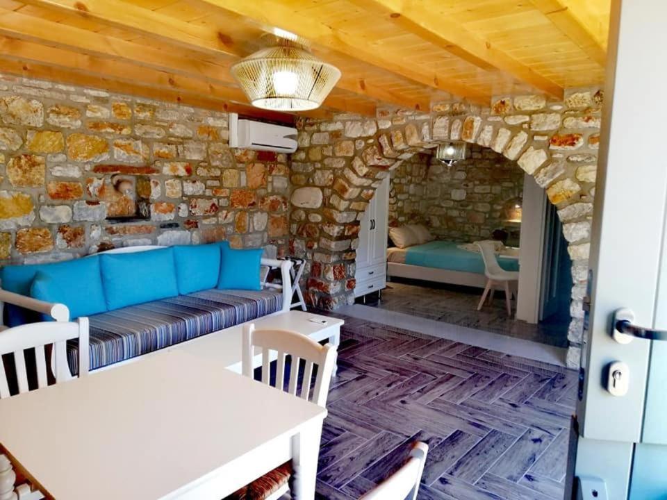 una camera con divano e letto in un muro di pietra di Delfinaki Lionas Boutique Apartments a Lionas