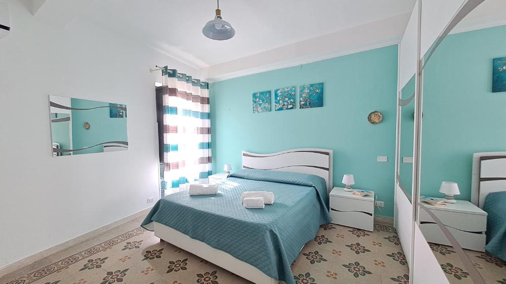 een blauwe slaapkamer met een bed en een spiegel bij Sky Apartment by Casa in mente in Cefalù