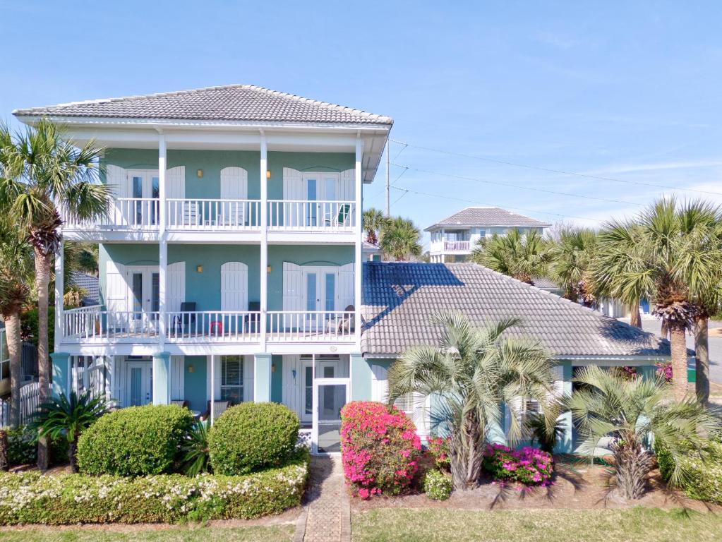 a large blue house with palm trees and bushes at Martinique Close To Beach Pet Friendly in Destin