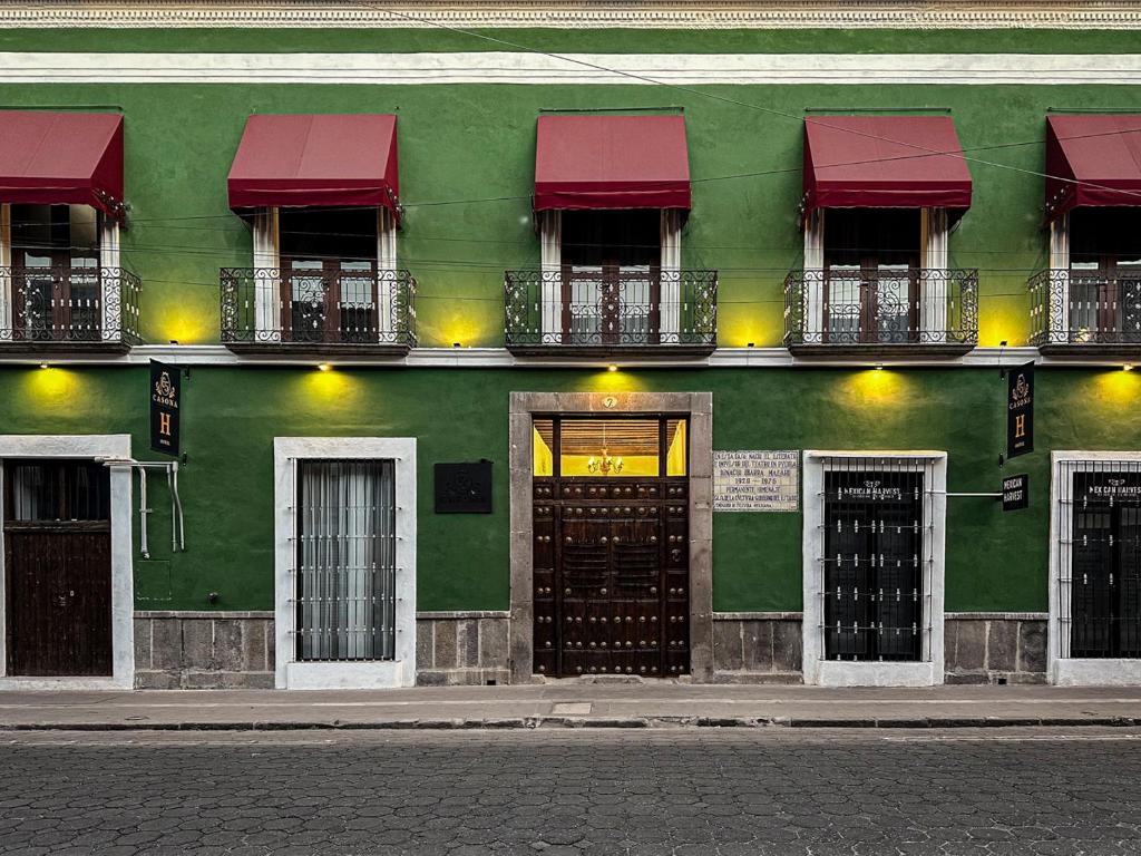 プエブラにあるHOTEL BOUTIQUE CASONA 65の赤い日よけとドアが付いた緑の建物