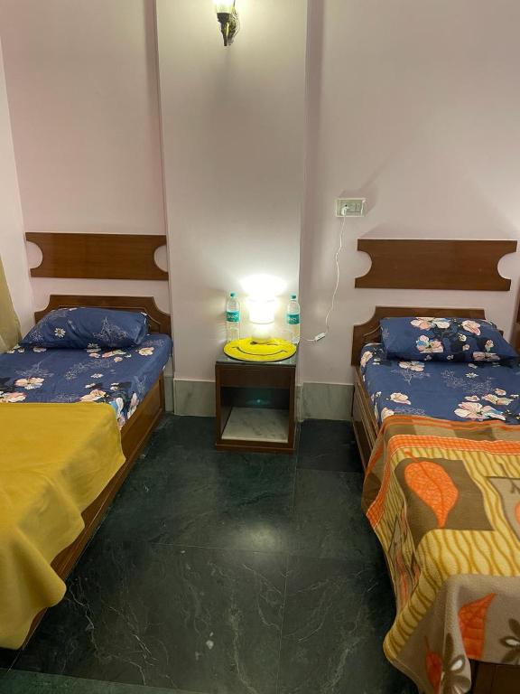 een kamer met 2 bedden en een tafel met een lamp bij Krisha's homestay in Vrindāvan