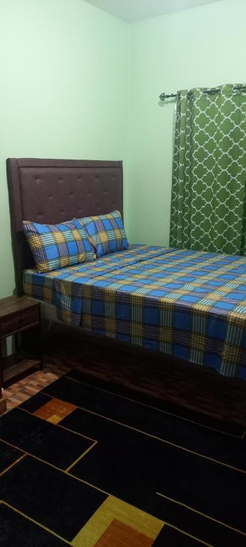 a bedroom with a bed with a blue plaid blanket at Mansfield Inn Ocho Rios in Ocho Rios