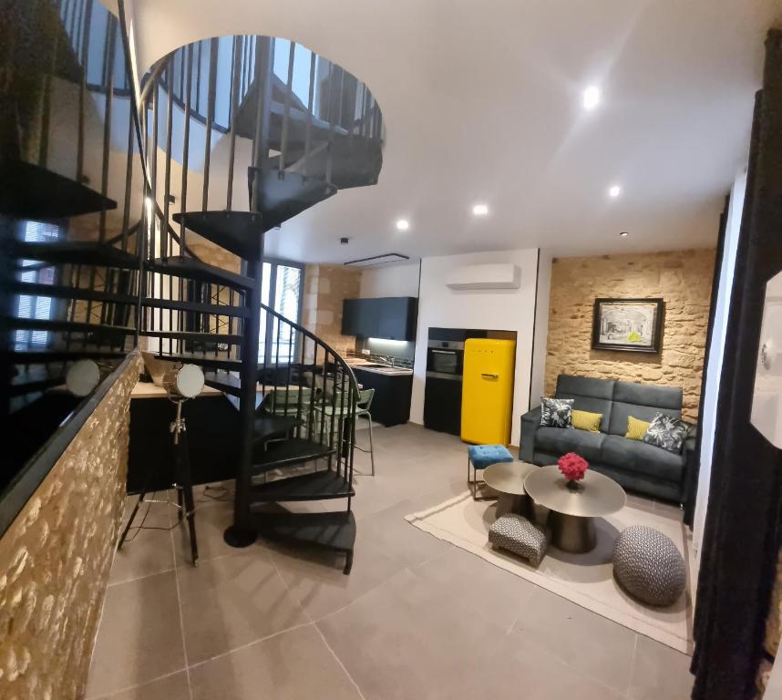 a living room with a spiral staircase in a house at Duplex Luxe avec parking Sarlat centre in Sarlat-la-Canéda