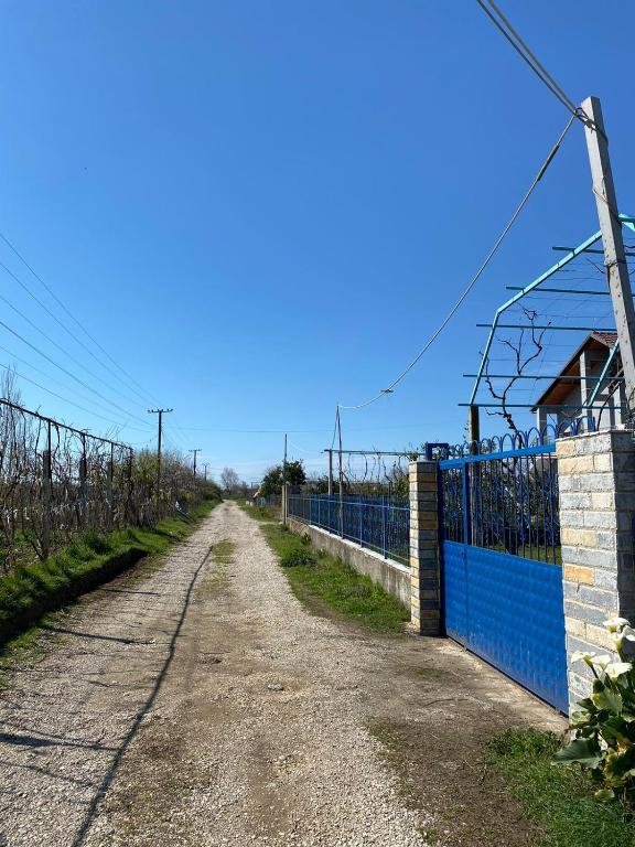 a dirt road next to a blue fence at Bert-House close to the sea in Lezhë