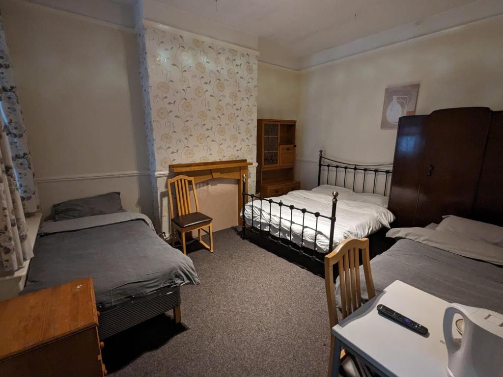 a bedroom with two beds and a desk and a table at OYO Ormsby Townhouse in Middlesbrough