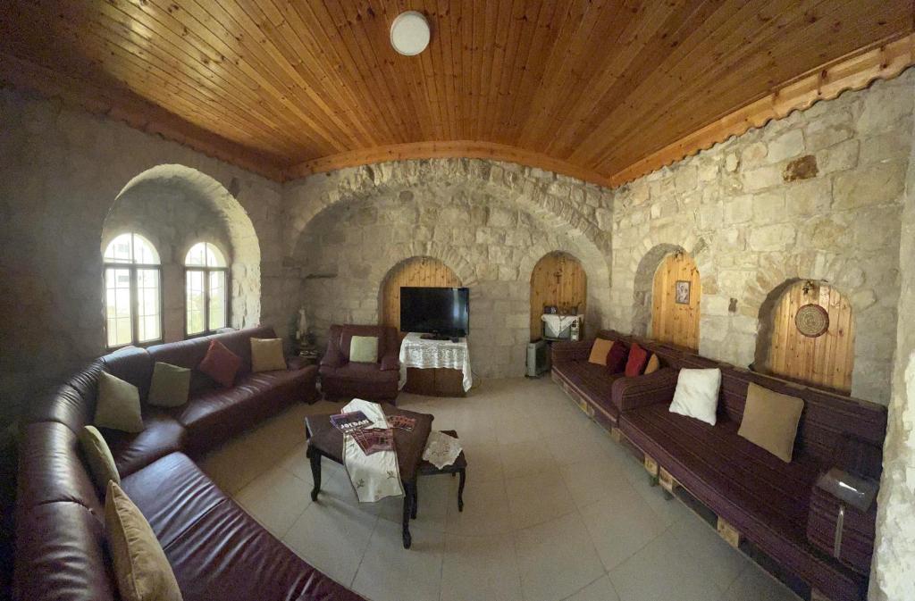 una sala de estar con sofás de cuero y una pared de piedra. en Al Karak House, en Kerak