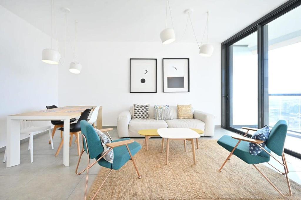 een woonkamer met een bank en een tafel en stoelen bij Yellow blue by HolyGuest in Tel Aviv