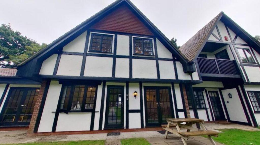 una casa blanca y negra con una mesa de picnic delante en 33 Tudor Court, en Hayle