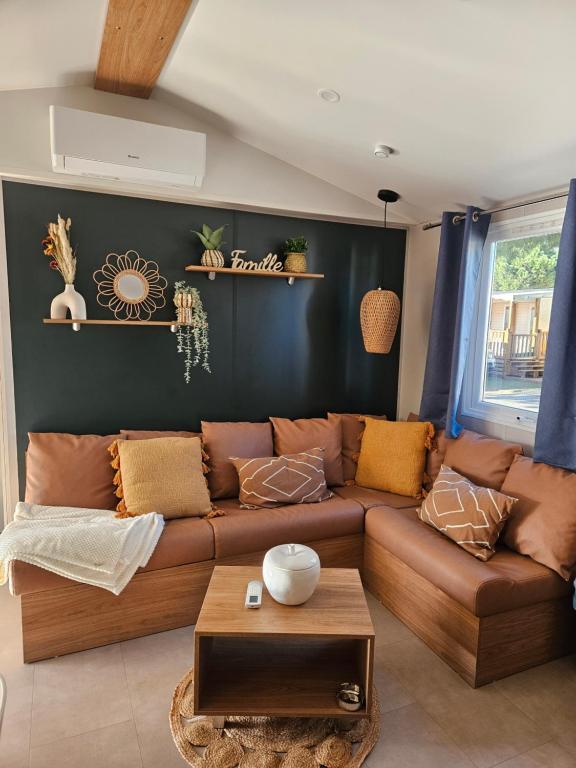 a living room with a brown couch and a table at Casa Luisa Mobil Home in Canet-en-Roussillon