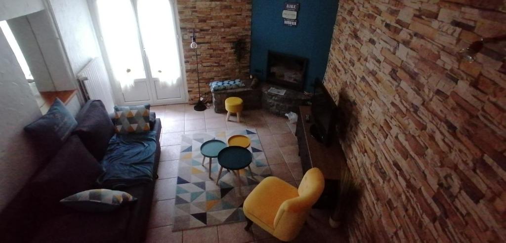 a living room with a couch and a brick wall at Grande maison au charme chaleureux hiver comme été in La Bourboule