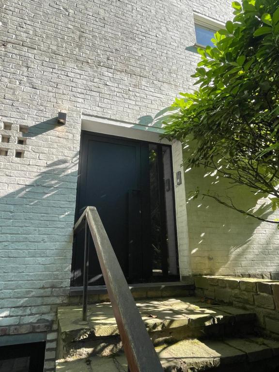 una puerta a un edificio de ladrillo con una escalera al lado en @Tiny Baron Appart - Kraainem en Kraainem