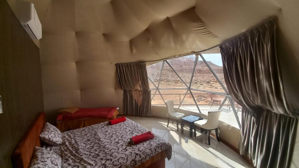 a bedroom with a bed and a large window at Al Raha Luxury Camp in Wadi Rum