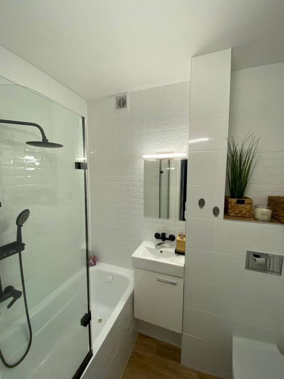 a white bathroom with a shower and a sink at Apartament Kasia in Wałbrzych