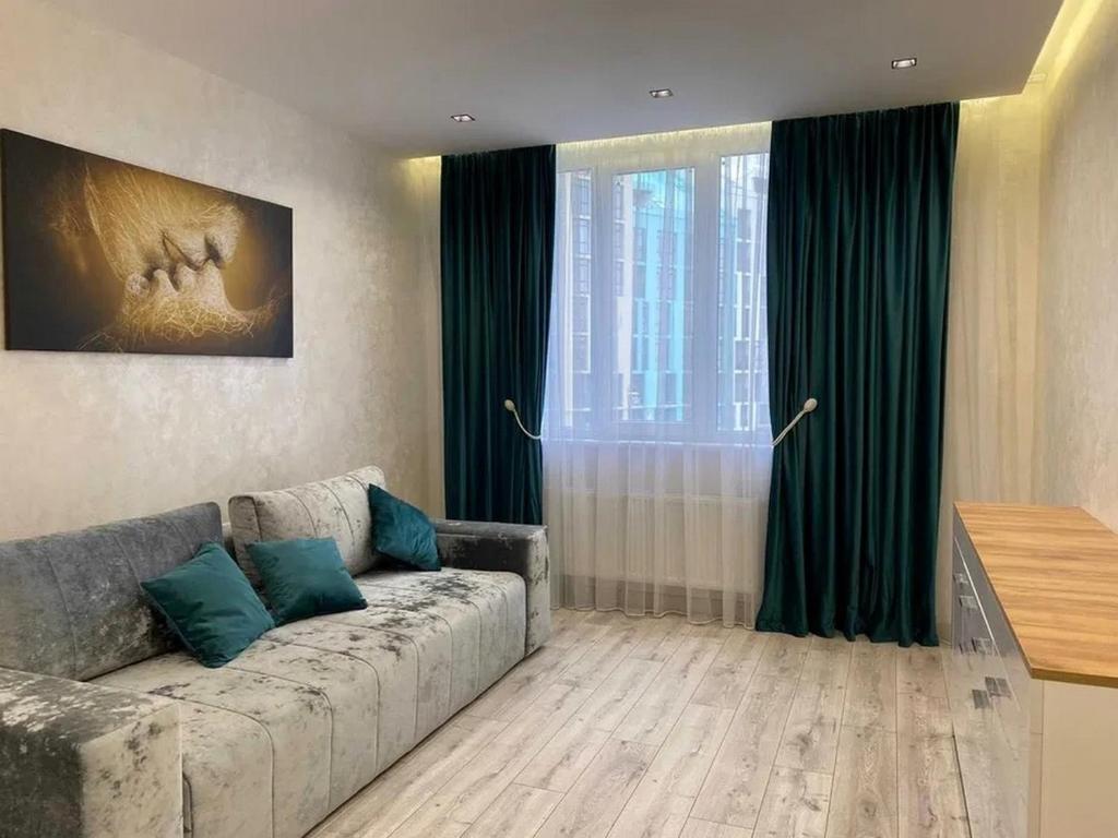 a living room with a couch in front of a window at апартаменти як вдома in Lviv
