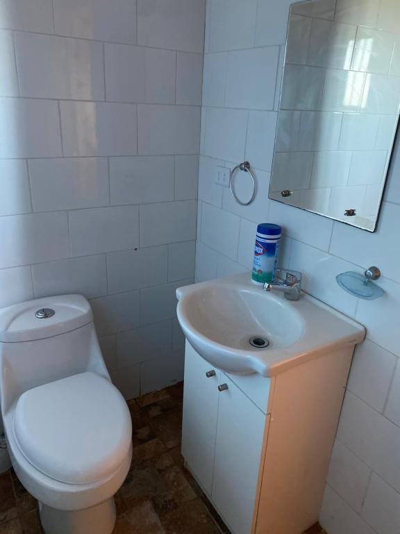 een witte badkamer met een toilet en een wastafel bij Bella cabaña sector residencial in Pelluhue