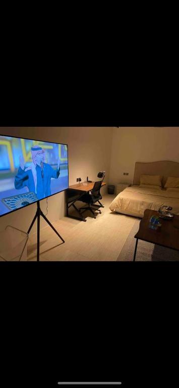 a bedroom with a bed and a large screen television at استديو بتصميم عصري ومريح في موقع مميز in Riyadh