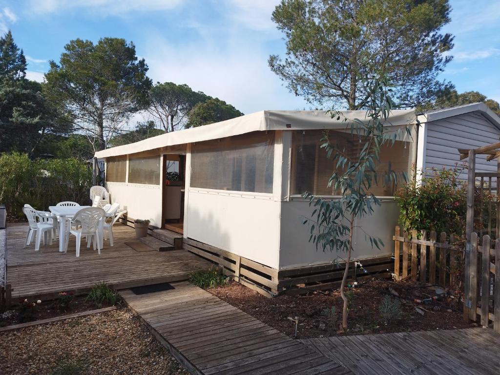 une petite maison avec une terrasse, une table et des chaises dans l'établissement Mobil home à louer dans camping des cigales le muy 5 étoiles, au Muy