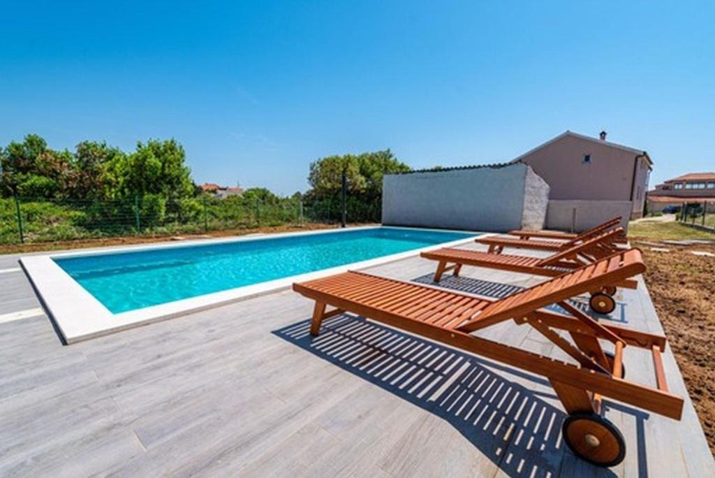 - une piscine avec 2 tables de pique-nique à côté dans l'établissement Wohnung in Nin mit Garten, gemeinsamem Pool und Terrasse, à Nin