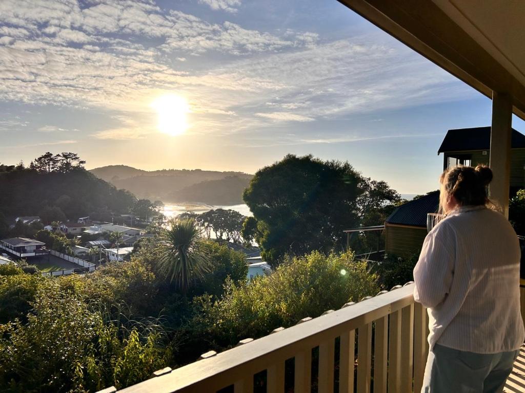 a woman standing on a balcony looking at the sunset at High Tides in Ngunguru