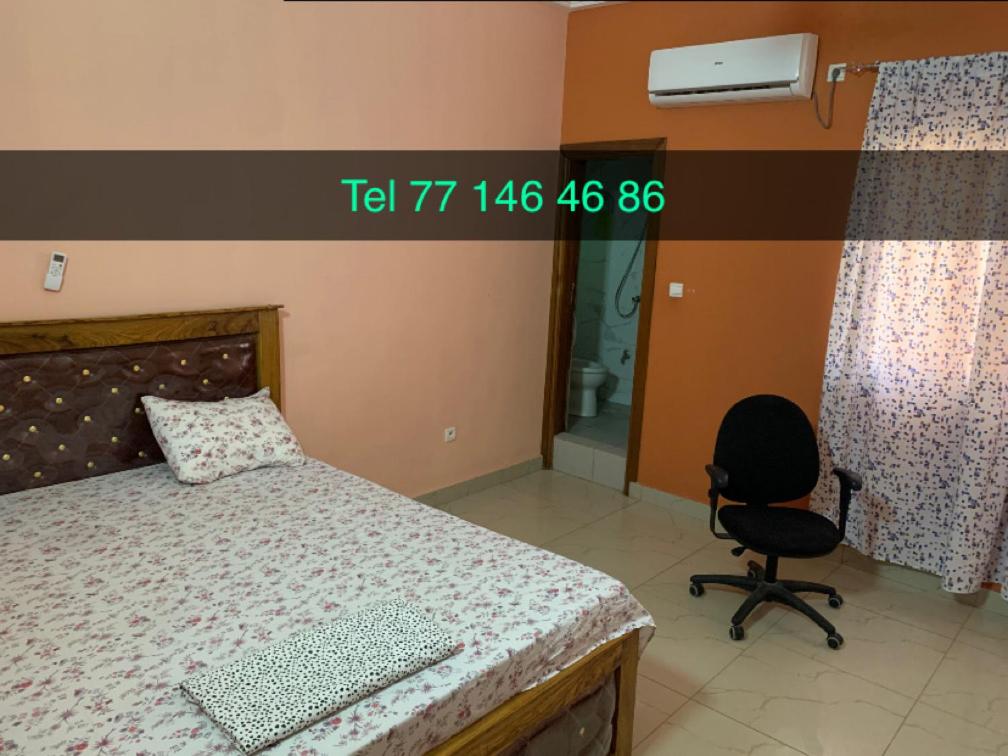 1 dormitorio con 1 cama y 1 silla en Moustapha, en Kaolack