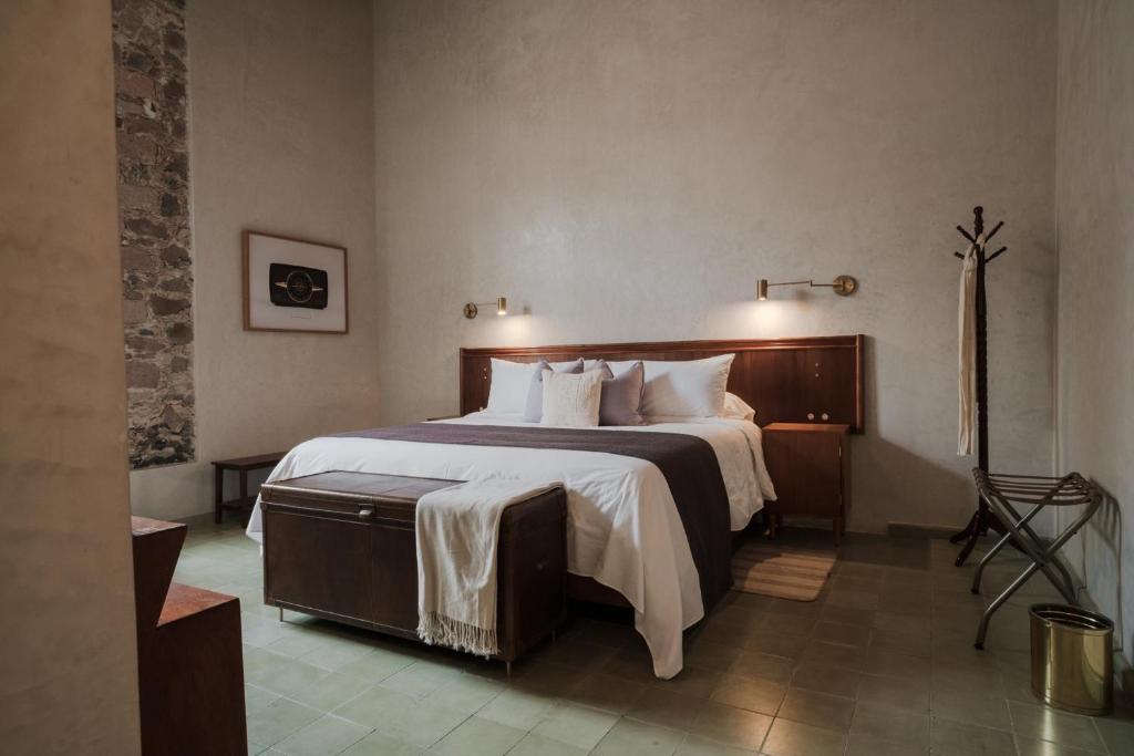 een slaapkamer met een groot bed met witte lakens en kussens bij Hotel Hércules in Querétaro