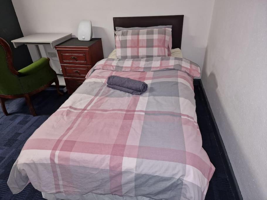 uma cama com um cobertor rosa e branco e uma secretária em Room near East Midland Airport 5 em Kegworth