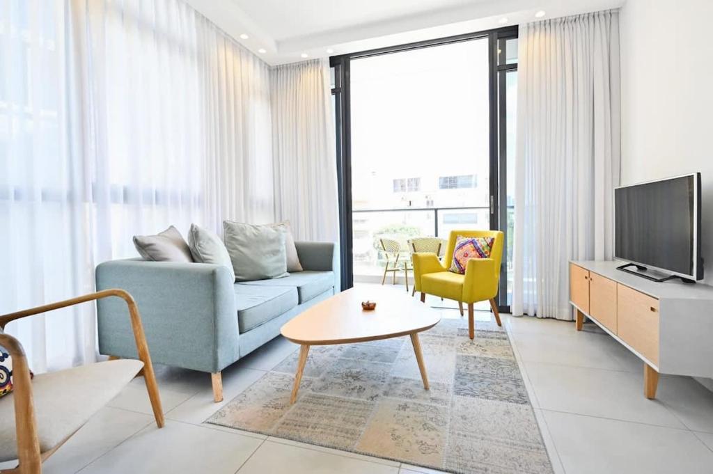 ein Wohnzimmer mit einem blauen Sofa und einem TV in der Unterkunft New Day by HolyGuest in Tel Aviv