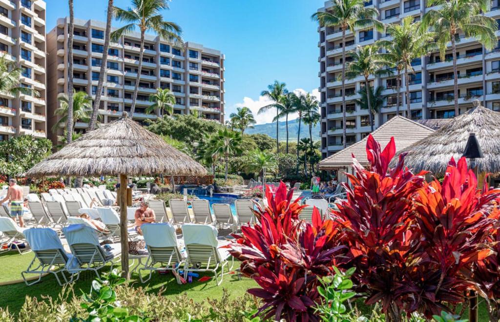 eine Gruppe von Stühlen und Sonnenschirmen in einem Resort in der Unterkunft The Kaanapali Alii By Maui Resort Rentals in Lahaina