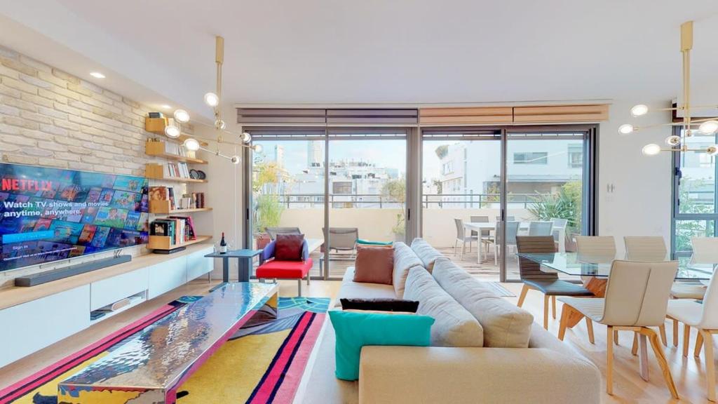 een woonkamer met een bank en een tafel bij Colorful Shenkin 3-BR by HolyGuest in Tel Aviv