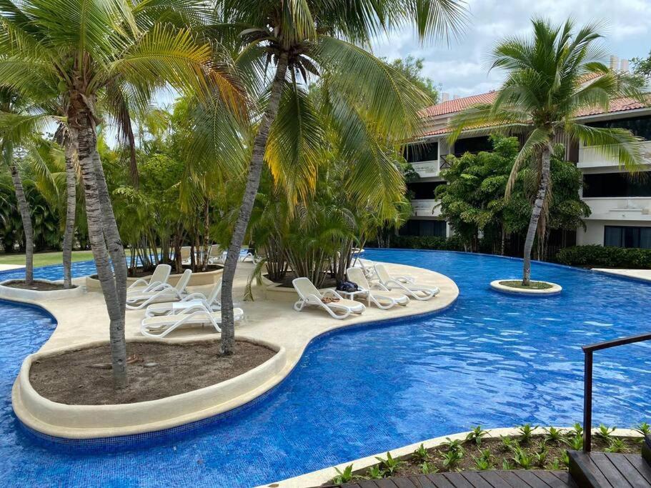 un complejo con piscina con tumbonas y palmeras en Tower Suite Hotel Coronado, en Playa Coronado