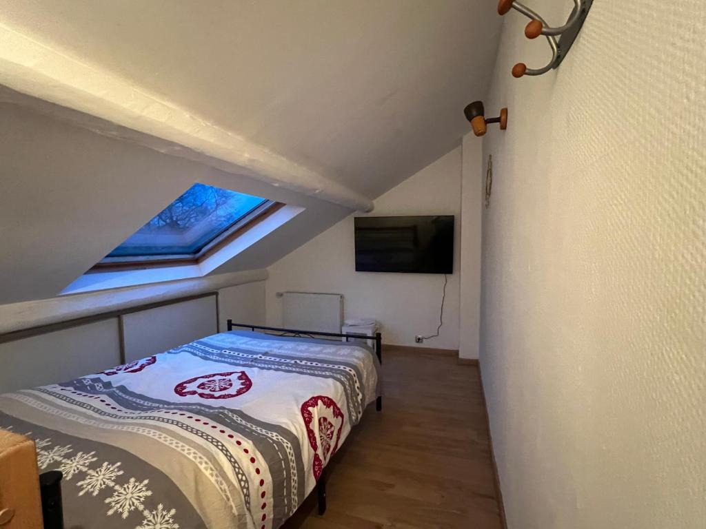 1 dormitorio en el ático con 1 cama y TV en Belle chambre à la frontière Luxembourg, en Audun-le-Tiche