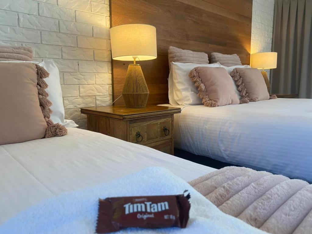 une chambre d'hôtel avec deux lits et une lampe dans l'établissement Beachmere Palms Motel, à Beachmere