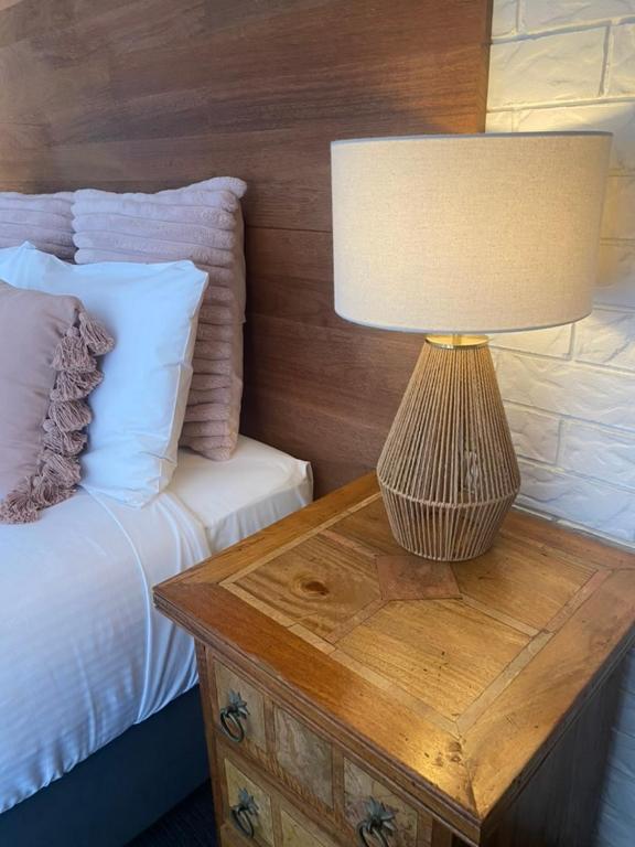 a lamp on a wooden table next to a bed at Beachmere Palms Motel in Beachmere